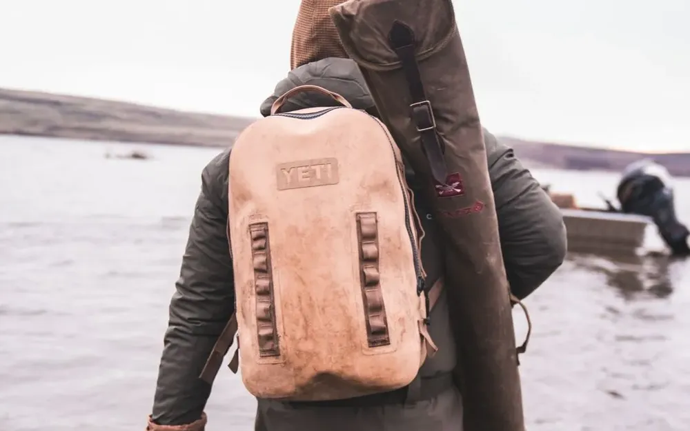 A waterfowl hunter wading into a lake with a KICK-EEZ gun case