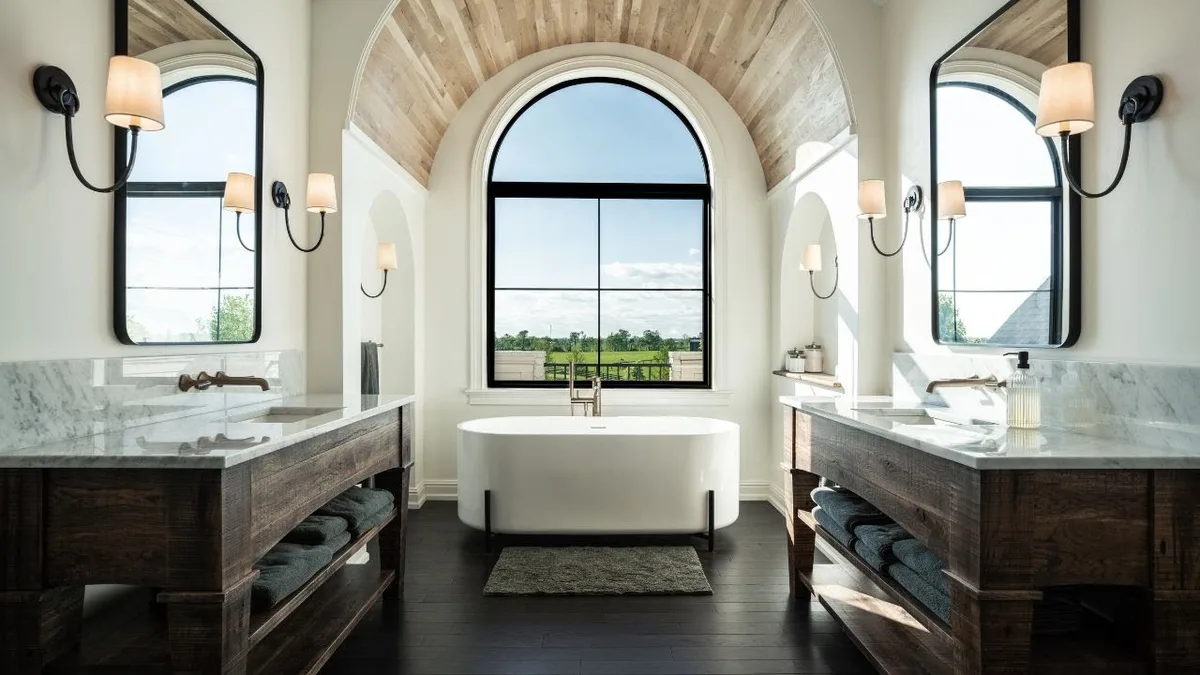 A remodeled bathroom with a freestanding tub, arched window and double vanities
